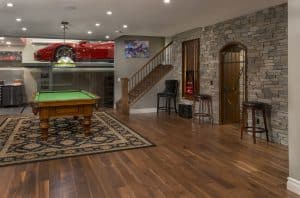 An incredible custom basement development with a garage featured through a glass wall.