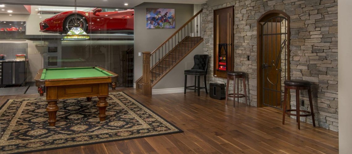 An incredible custom basement development with a garage featured through a glass wall.