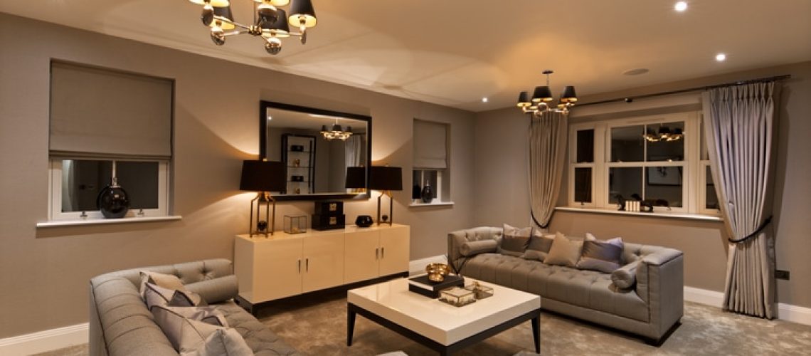 a six seater lounge or reception room in a luxury new home with two comfortable sofas, photographed during the evening with all of the lights on.