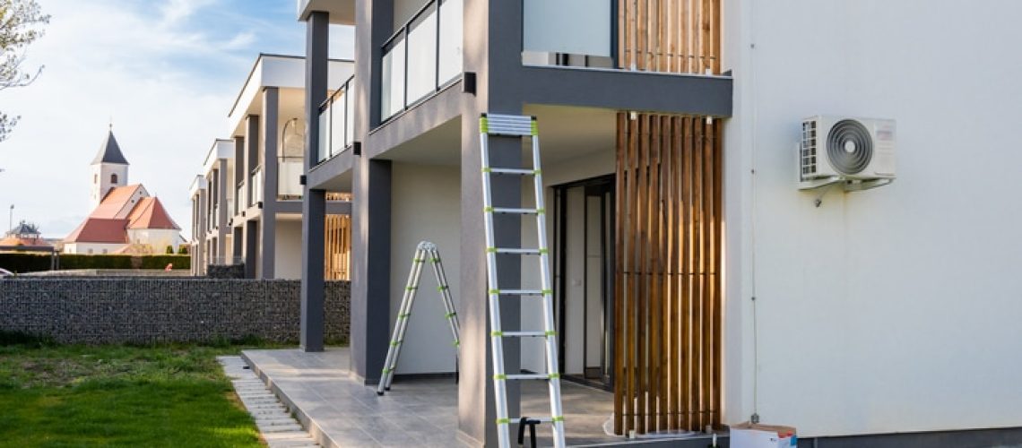 Paint equipment and ladders outside modern house against sky during sunny day
