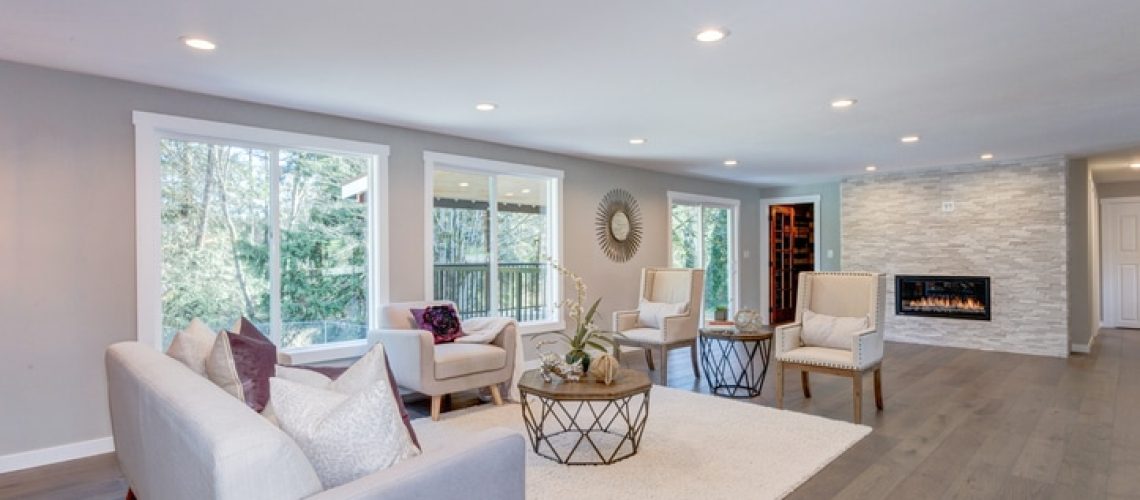 Spacious white living area with stone wall fireplace.